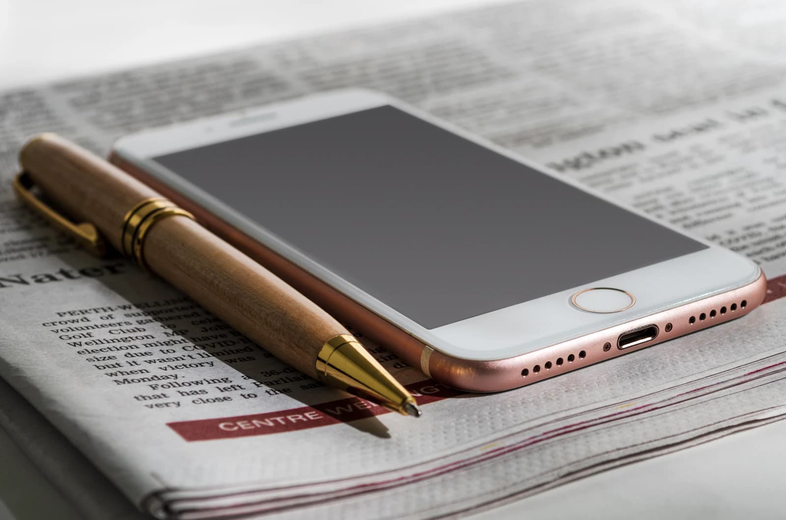 Phone, newspaper, and pen representing documentation for a Tea Dating Advice removal request